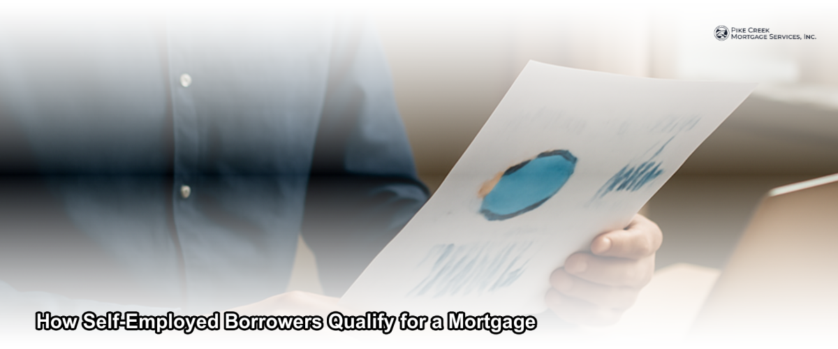 Self-employed borrower reviewing mortgage documents at a desk with a laptop and financial paperwork in a home office setting