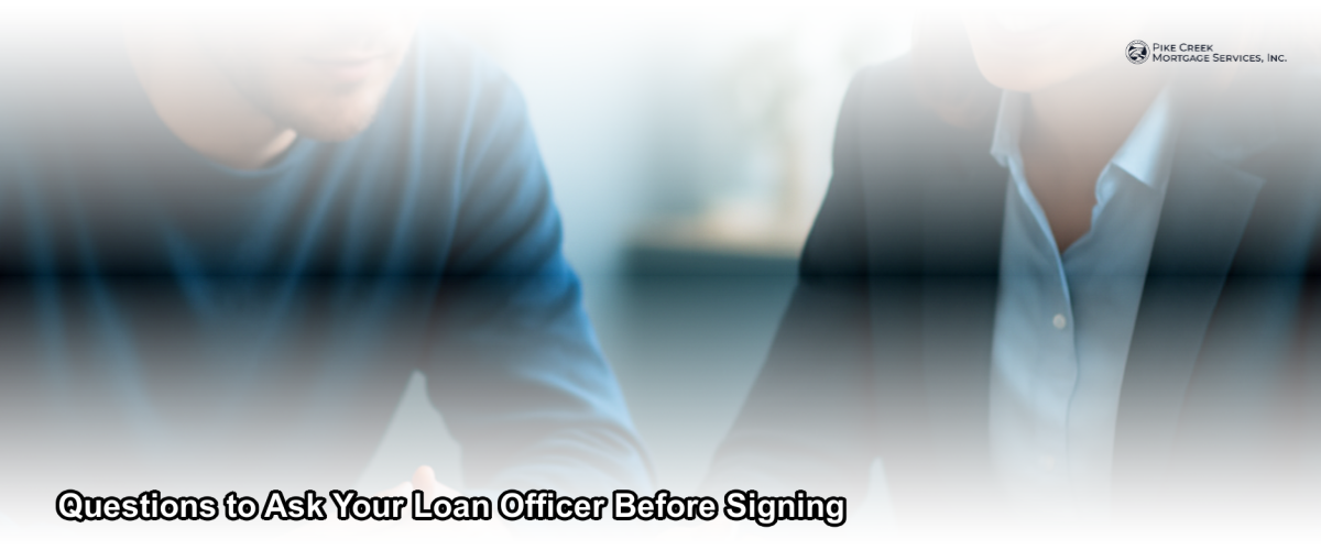 A borrower reviewing mortgage documents with a loan officer at a desk in a professional office setting