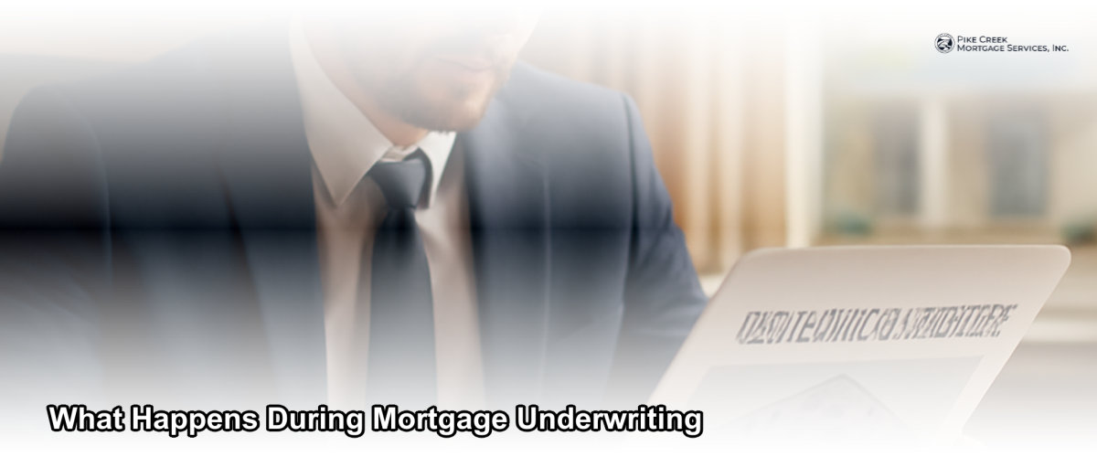 A loan officer reviewing mortgage documents at a desk with a home in the background, representing the underwriting review process