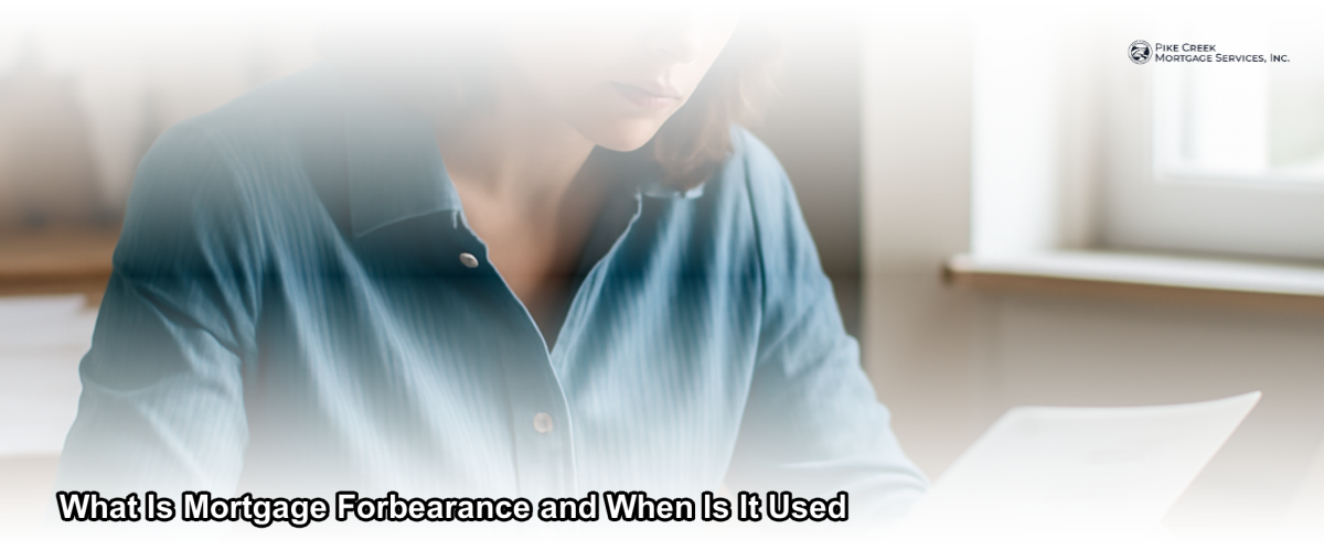A homeowner sitting at a kitchen table reviewing mortgage documents with a calm, focused expression, representing financial planning during hardship